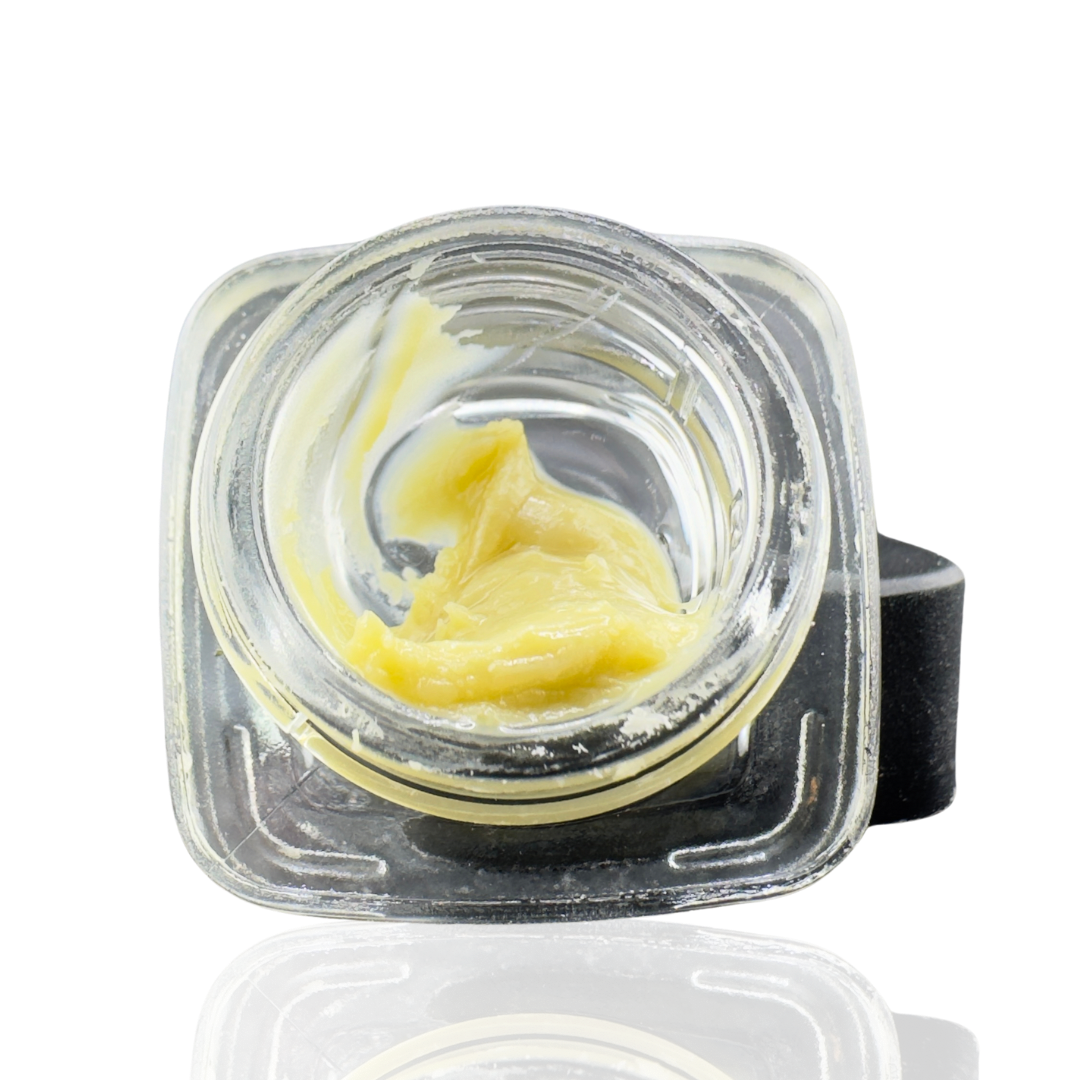 A clear container with a lid, holding a smooth, yellow cannabis extract or concentrate.